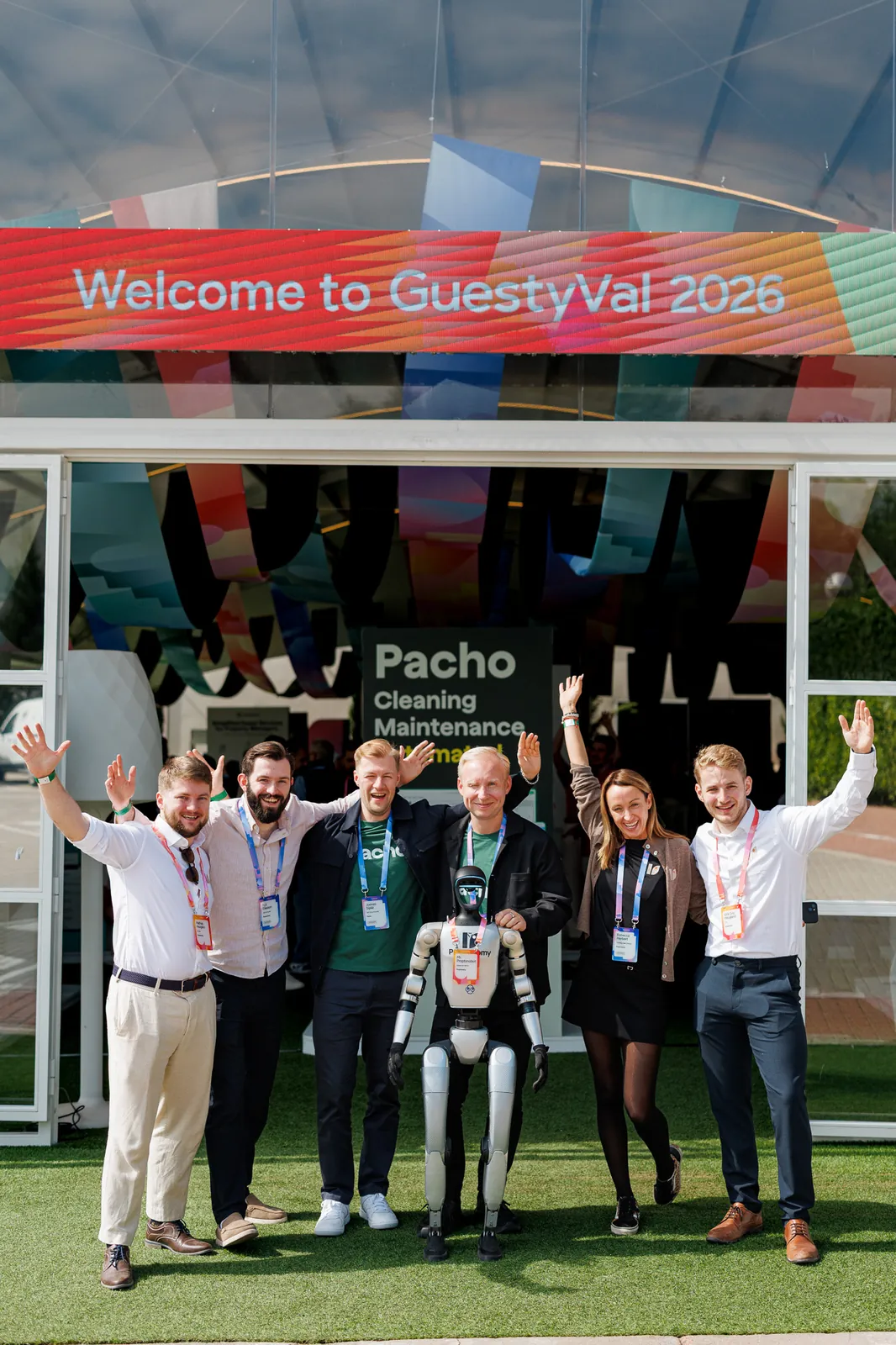 The Proptonomy team and friends cheering with Proptonobot under the Welcome to GuestyVal 2026 banner
