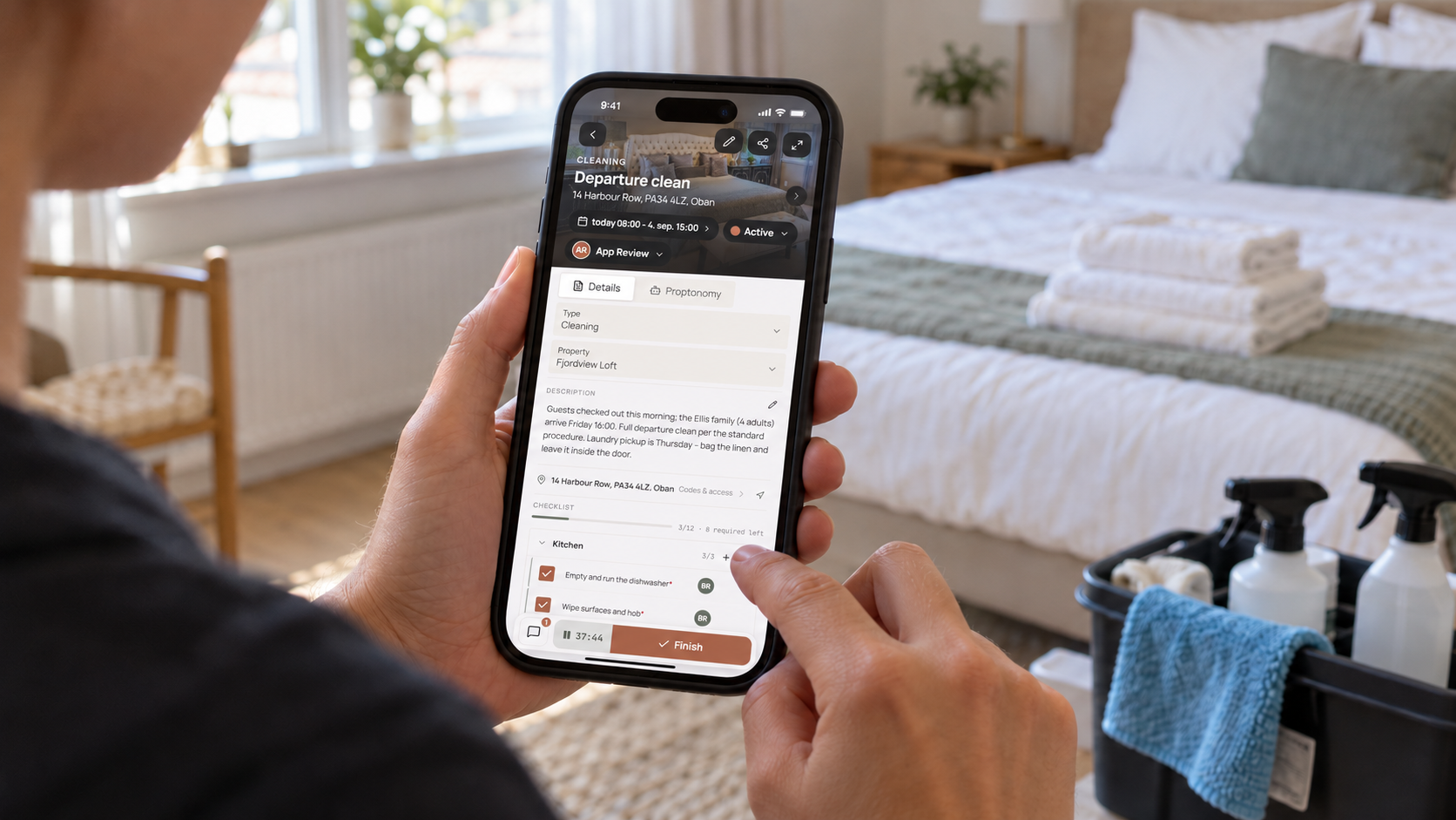 Cleaner using Proptonomy's task checklist on an iPhone in an apartment bedroom